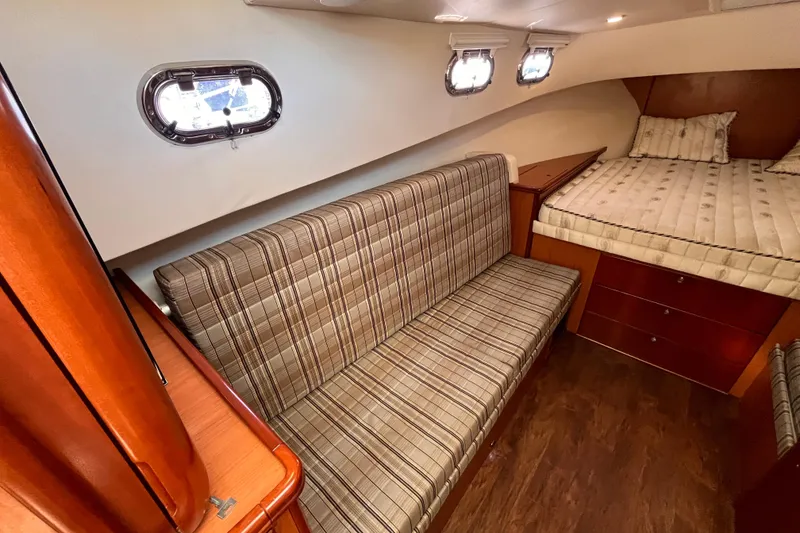 Slide: The Image of Interior of 2009 Mainship Pilot 31 boat with plaid seating and cozy sleeping area. - 21