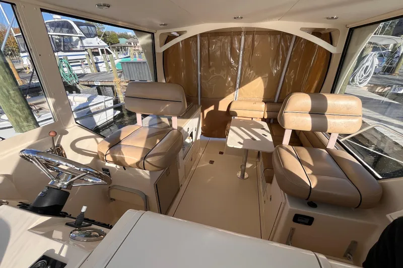 Slide: The Image of 2009 Mainship Pilot 31 interior with beige seating and steering wheel, docked at marina. - 36