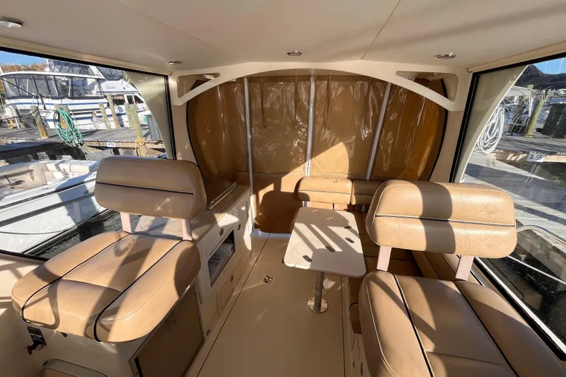 Slide: The Image of 2009 Mainship Pilot 31 interior with tan seating and table, docked at marina. - 37