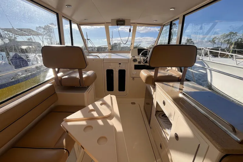 Slide: The Image of 2009 Mainship Pilot 31 interior with helm, seating, and windows overlooking marina. - 42