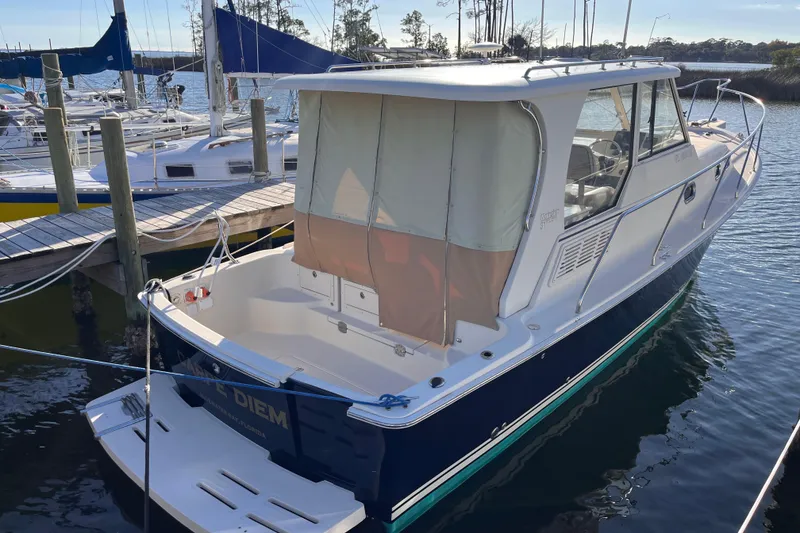Slide: The Image of 2009 Mainship Pilot 31 boat docked at marina, featuring enclosed cabin and sleek design. - 46