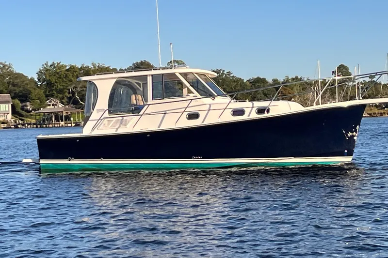 Slide: The Image of 2009 Mainship Pilot 31 boat on calm water, side view, clear sky background. - 47
