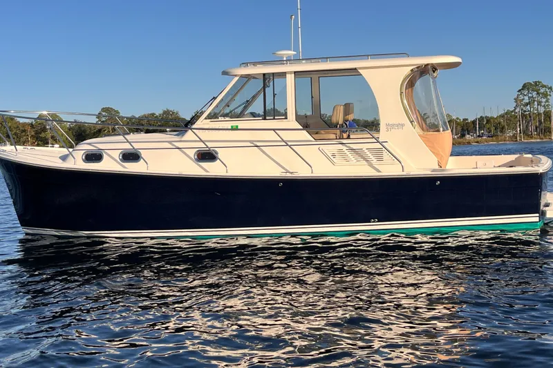 Slide: The Image of 2009 Mainship Pilot 31 boat on calm water, side view, clear sky background. - 49