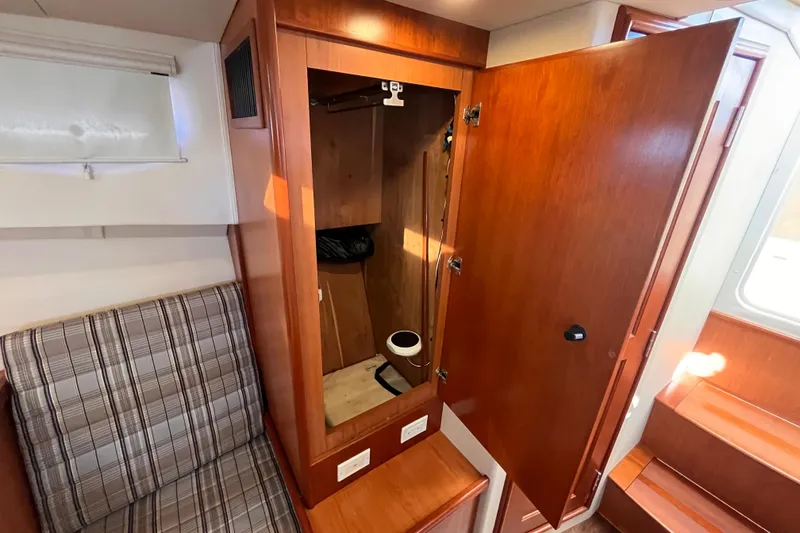 Slide: The Image of 2009 Mainship Pilot 31 interior with open wooden closet and plaid seating. - 8