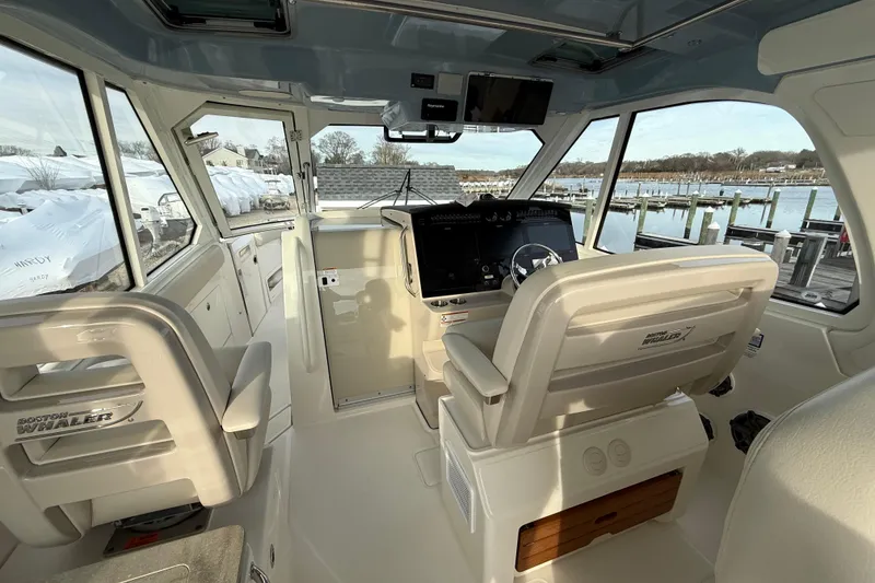 Slide: The Image of 2021 Boston Whaler 380 Realm helm with modern controls and panoramic marina view. - 16