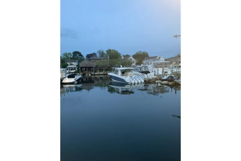 Slide: The Image of 2021 Boston Whaler 380 Realm docked in a serene marina setting. - 27
