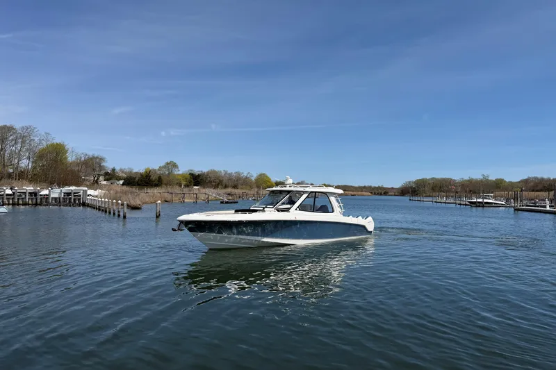 Slide: The Image of 2021 Boston Whaler 380 Realm cruising on a calm river under a clear blue sky. - 31