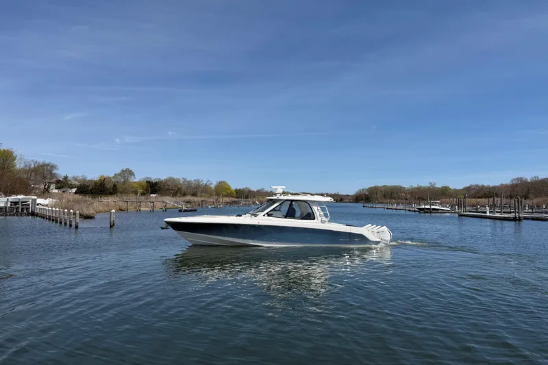 Slide: The Image of 2021 Boston Whaler 380 Realm cruising on a calm river under a clear blue sky. - 32
