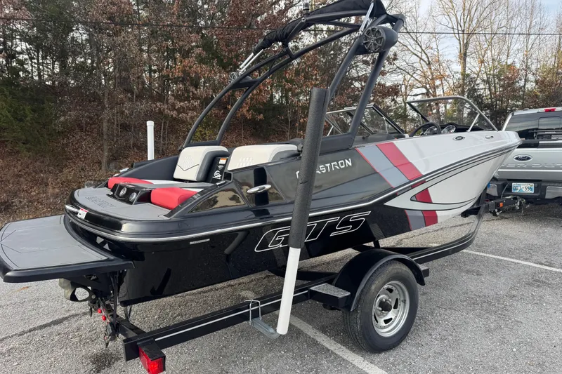 Slide: The Image of 2015 Glastron GTS 187 boat on trailer, parked outdoors with trees in background. - 12