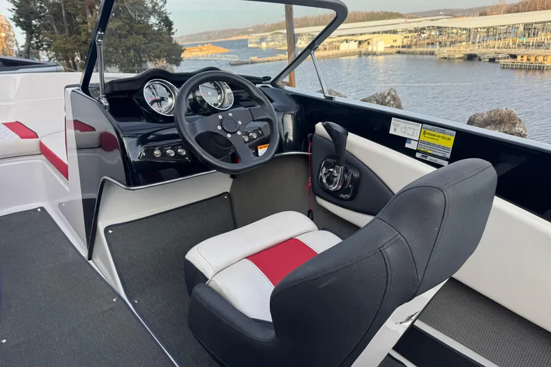 Slide: The Image of 2015 Glastron GTS 187 boat interior with steering wheel and dashboard, overlooking a marina. - 21