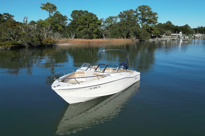 Slide: The Image of 2016 Scout 210 Dorado boat on calm water, surrounded by lush greenery. - 2