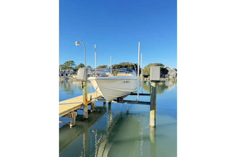 Slide: The Image of 2017 Scout 210 Dorado boat on lift at dock, clear blue sky background. - 8