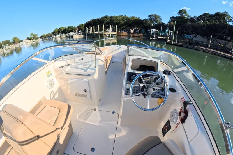 Slide: The Image of 2017 Scout 210 Dorado boat interior with steering wheel, docked on a calm lake. - 9