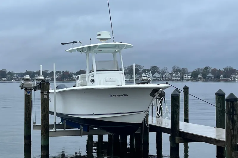 The Image of 2015 Sea Hunt Gamefish 27 boat docked on a lift by a calm waterfront. - 0