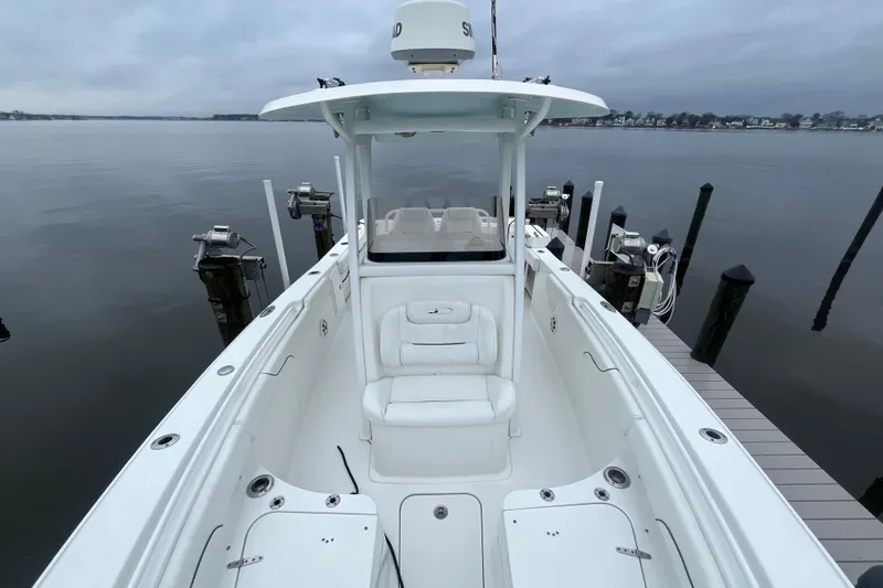 Slide: The Image of 2015 Sea Hunt Gamefish 27 boat docked on calm waters, showcasing spacious deck and seating. - 11