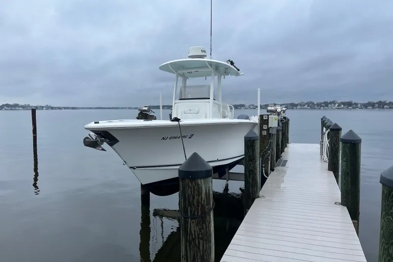 Slide: The Image of 2015 Sea Hunt Gamefish 27 docked on a cloudy day by the water. - 2