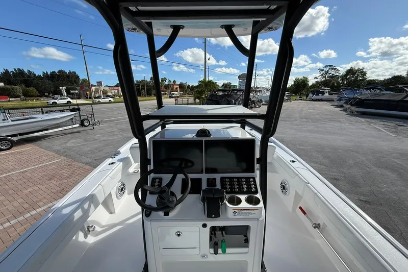 Slide: The Image of 2023 Caymas 28 HB Twin boat dashboard with steering wheel and controls, parked outdoors. - 25