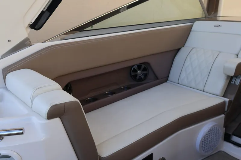 Slide: The Image of 2018 Regal 28 Express boat interior with beige and white seating, cup holders, and speaker. - 14