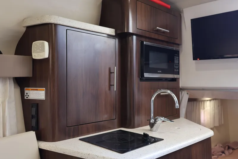 Slide: The Image of 2018 Regal 28 Express boat interior kitchen with microwave, sink, and TV. - 33