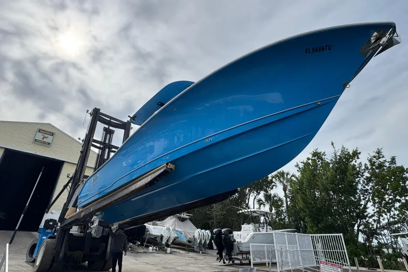 Slide: The Image of 2024 Sea Hunt Ultra 305 SE boat lifted in marina, showcasing sleek blue hull design. - 20