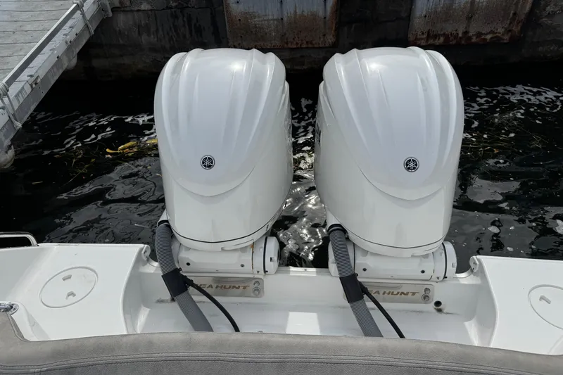 Slide: The Image of Twin outboard engines on a 2024 Sea Hunt Ultra 305 SE boat docked by the water. - 3