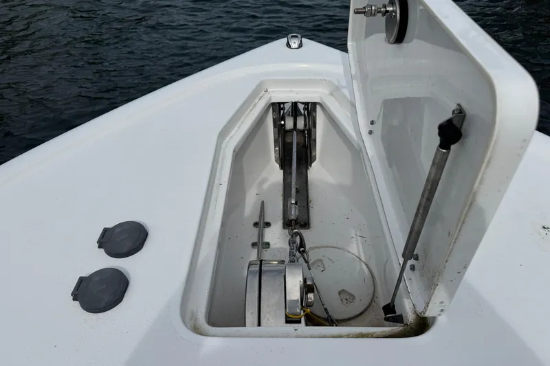 Slide: The Image of 2024 Sea Hunt Ultra 305 SE anchor compartment with open hatch on water. - 9
