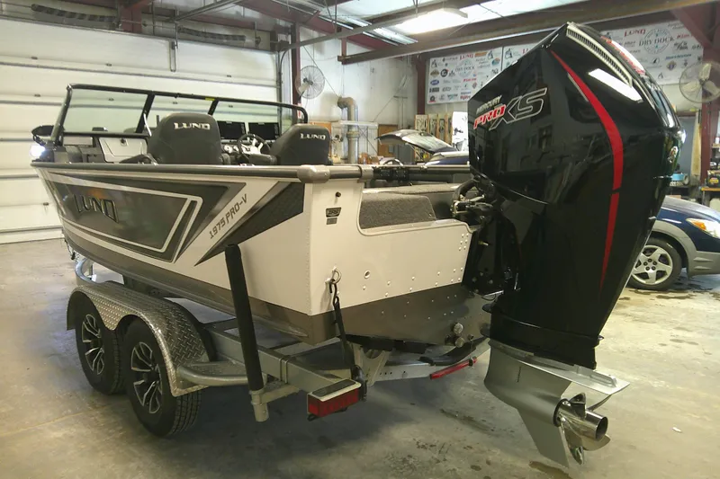 Slide: The Image of 2025 Lund 1975 Pro-V boat with Mercury Pro XS engine in a garage setting. - 2