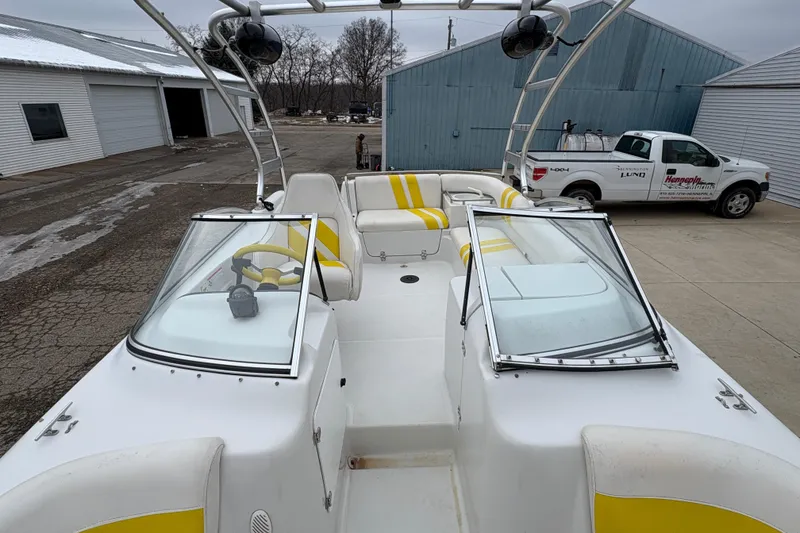 Slide: The Image of 2003 Splendor 240 Platinum boat with yellow accents, parked near industrial buildings. - 15
