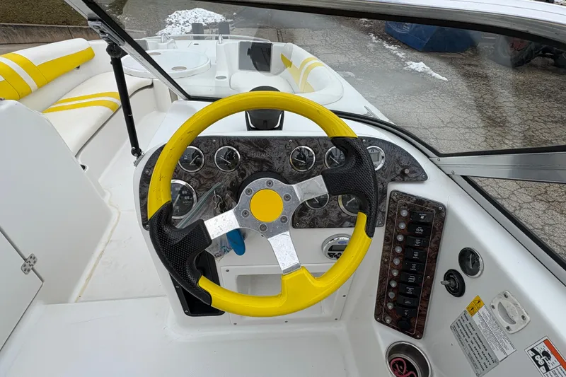 Slide: The Image of Steering wheel of 2003 Splendor 240 Platinum boat with yellow accents and dashboard controls. - 18