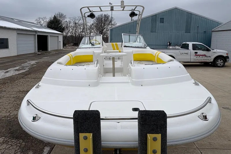 Slide: The Image of 2003 Splendor 240 Platinum boat with yellow seating, parked outdoors near buildings. - 8