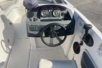 Slide: The Image of 2018 Bayliner 210 Deck Boat cockpit with steering wheel and dashboard controls. - 7