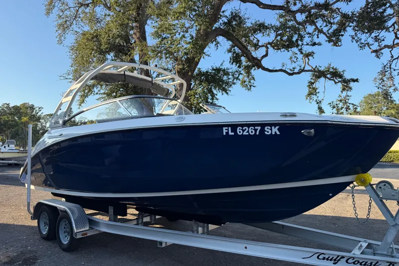 Slide: The Image of 2021 Yamaha Boats 252S on trailer, parked outdoors under trees. - 2