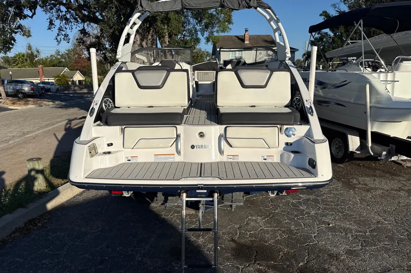 Slide: The Image of 2021 Yamaha Boats 252S, rear view, showcasing seating and swim platform in a parking area. - 6