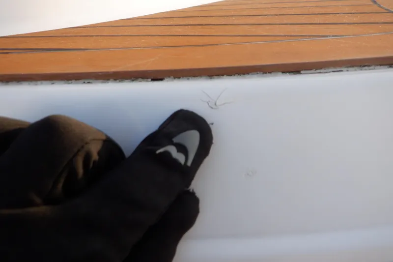 Slide: The Image of Gloved hand inspecting crack on 2013 Hurricane SunDeck 2400 IO boat surface. - 13