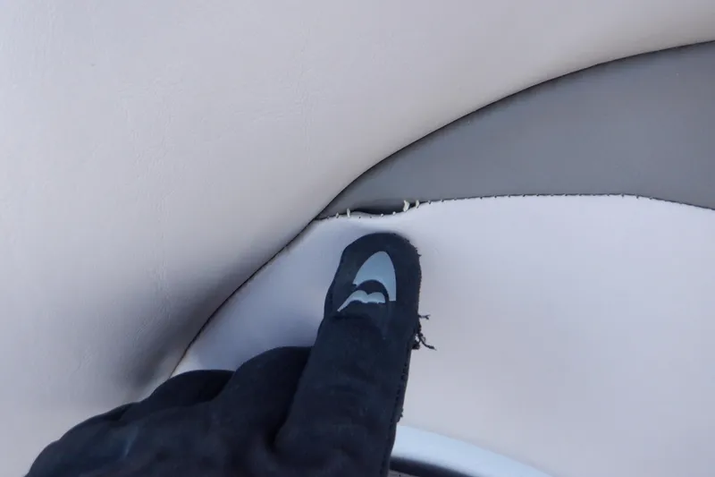 Slide: The Image of Gloved hand pointing at torn upholstery on 2013 Hurricane SunDeck 2400 IO boat. - 45