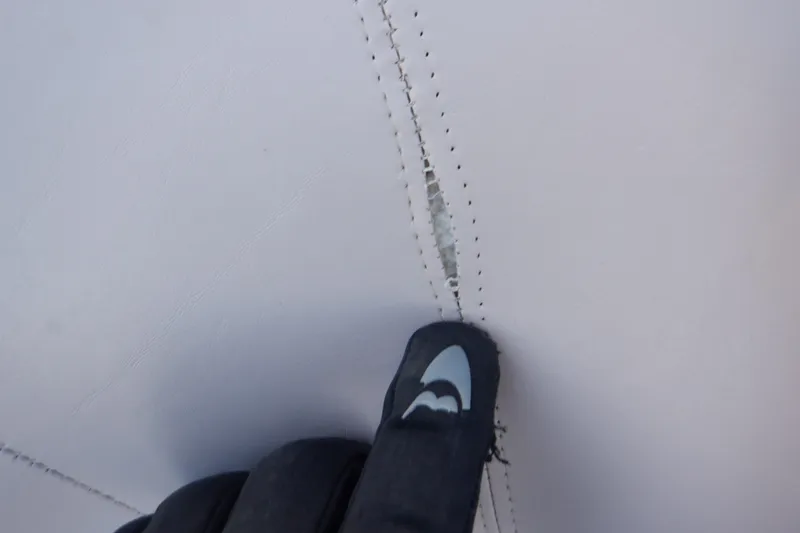 Slide: The Image of Close-up of a gloved hand inspecting a tear in 2013 Hurricane SunDeck 2400 IO upholstery. - 46