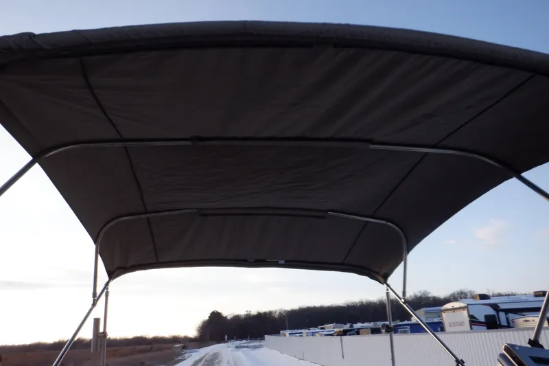 Slide: The Image of 2013 Hurricane SunDeck 2400 IO boat canopy against a clear sky. - 49