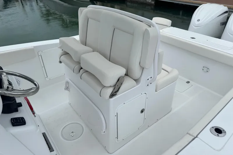 Slide: The Image of 2024 Sea Hunt Gamefish 27 Coffin Box boat interior with cushioned seating and steering wheel. - 10