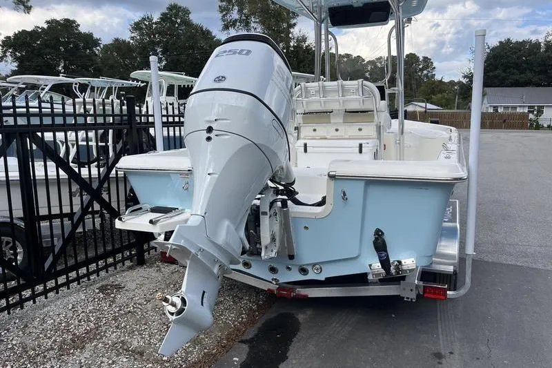 Slide: The Image of 2025 Bulls Bay 2400 boat with powerful outboard motor, parked near a fence. - 4