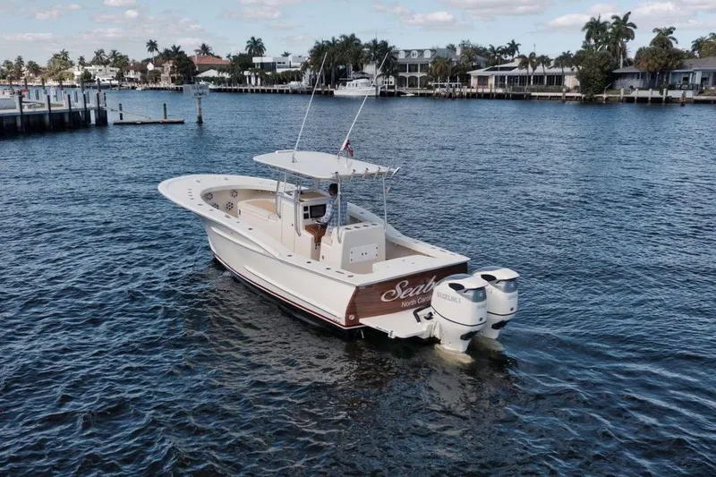 Slide: The Image of 2019 Custom Carolina boat on water, featuring dual Suzuki engines, near waterfront homes. - 4