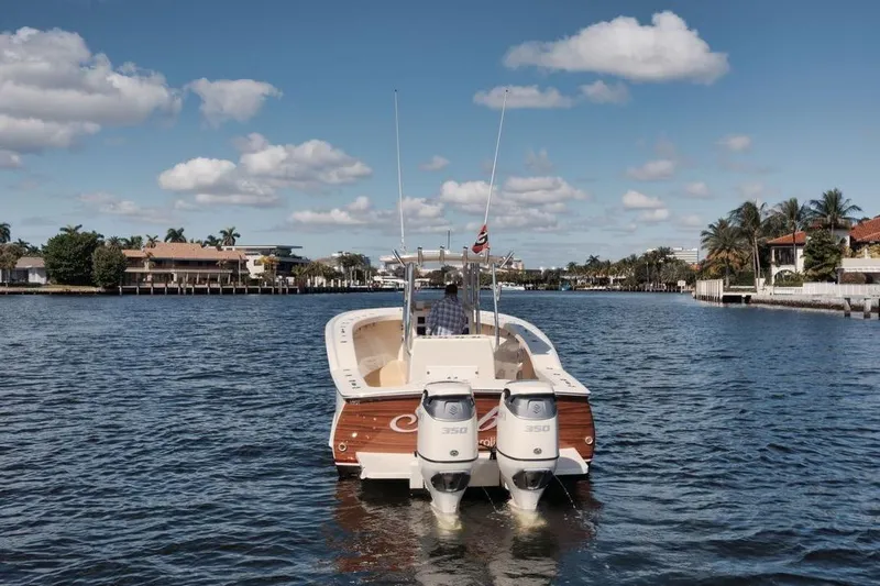 Slide: The Image of 2019 Custom Carolina boat cruising on a sunny waterway with palm trees and houses. - 7