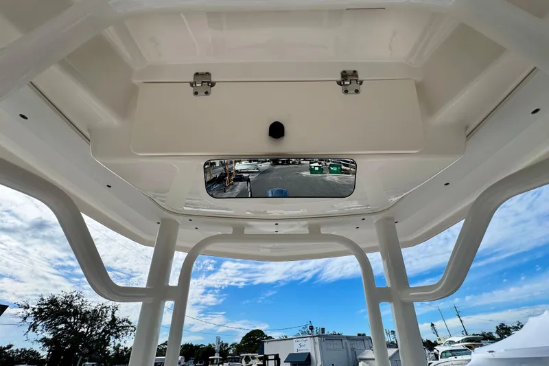Slide: The Image of 2017 Robalo 246 Cayman boat interior view with overhead storage and clear sky. - 17