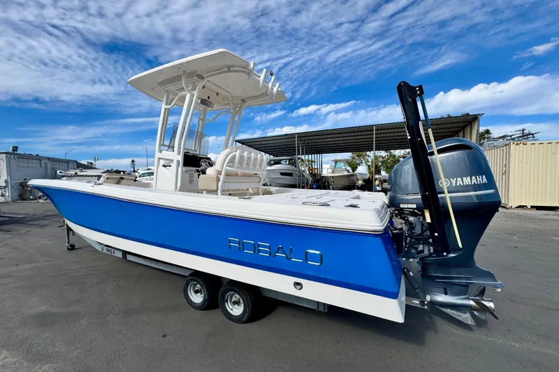 Slide: The Image of 2017 Robalo 246 Cayman boat with Yamaha engine, parked on a trailer under a blue sky. - 2