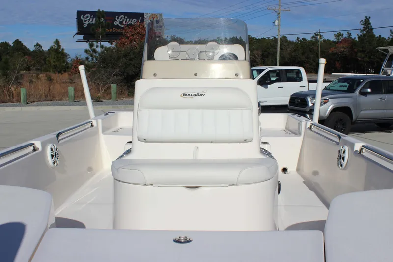 Slide: The Image of 2017 Bulls Bay 2000 boat interior with white seating and console, parked outdoors. - 10