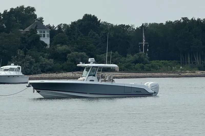 The Image of 2018 Boston Whaler 330 Outrage boat anchored near a wooded shoreline. - 0