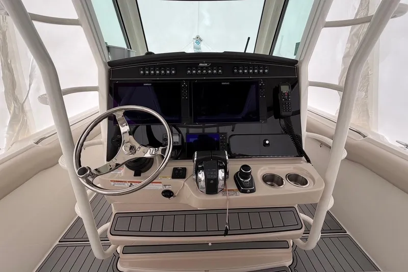 Slide: The Image of 2018 Boston Whaler 330 Outrage helm with steering wheel, controls, and navigation displays. - 17