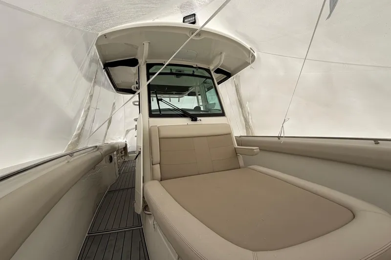 Slide: The Image of 2018 Boston Whaler 330 Outrage interior with beige seating under protective cover. - 22