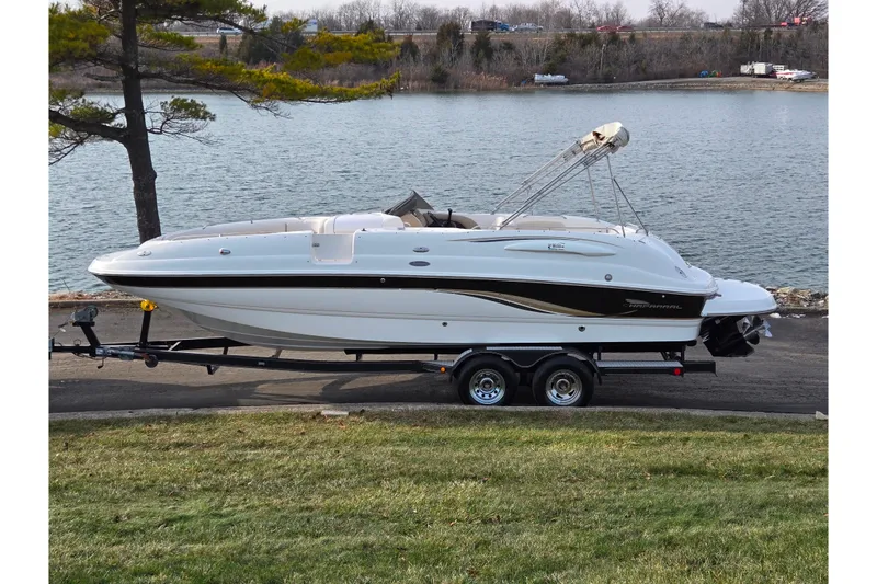 The Image of 2002 Chaparral Sunesta 242 boat on trailer by a lake, side view. - 0