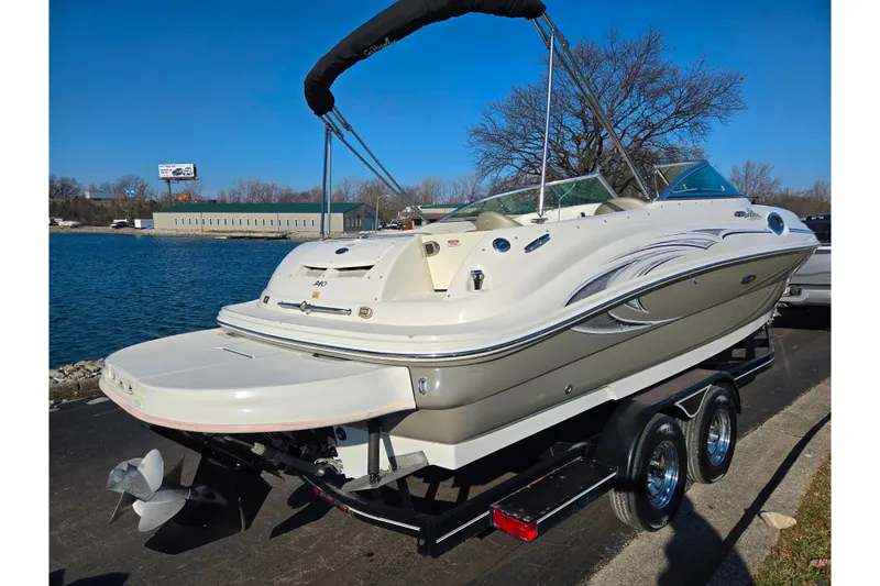 Slide: The Image of 2005 Sea Ray 240 Sundeck boat on trailer by waterfront, clear blue sky. - 1