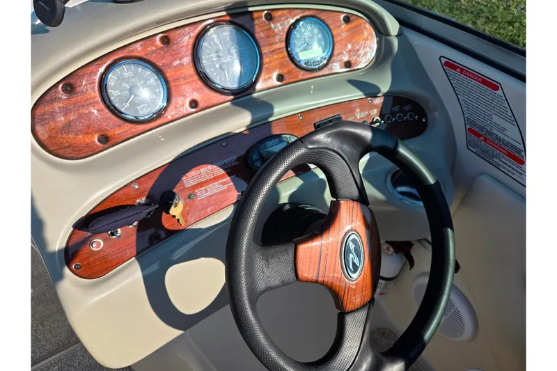 Slide: The Image of 2005 Sea Ray 240 Sundeck dashboard with wood accents and steering wheel. - 13